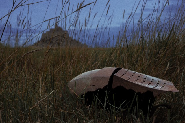A broken knight's helmet lying in tall grass